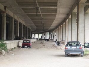 abandoned cars parked under a bridge
