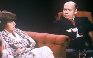 Man and woman sitting on red chairs 
